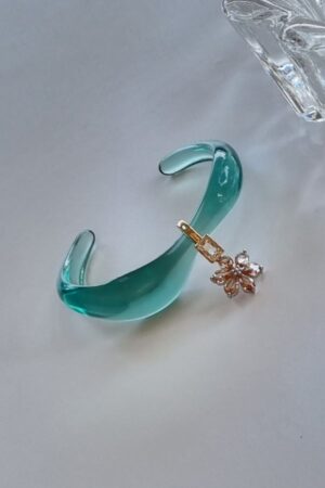 צמיד פתוח תכלת שקוף עם תליון קריסטל ופרח שמפניה על רקע בהיר